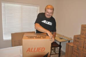 Professional Bakersfield movers providing packing services for a local move, carefully wrapping and boxing household items inside a home